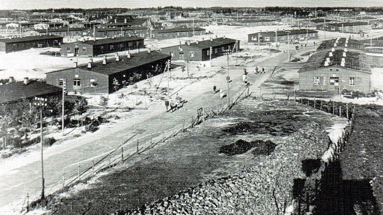 Historisches schwarz-weiß Foto. Luftaufnahme. In der Mitte ein Weg, links und rechts einstöckige Baracken.